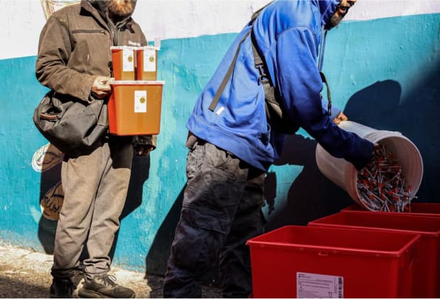 A man pouring a bucket of needles into another bucket